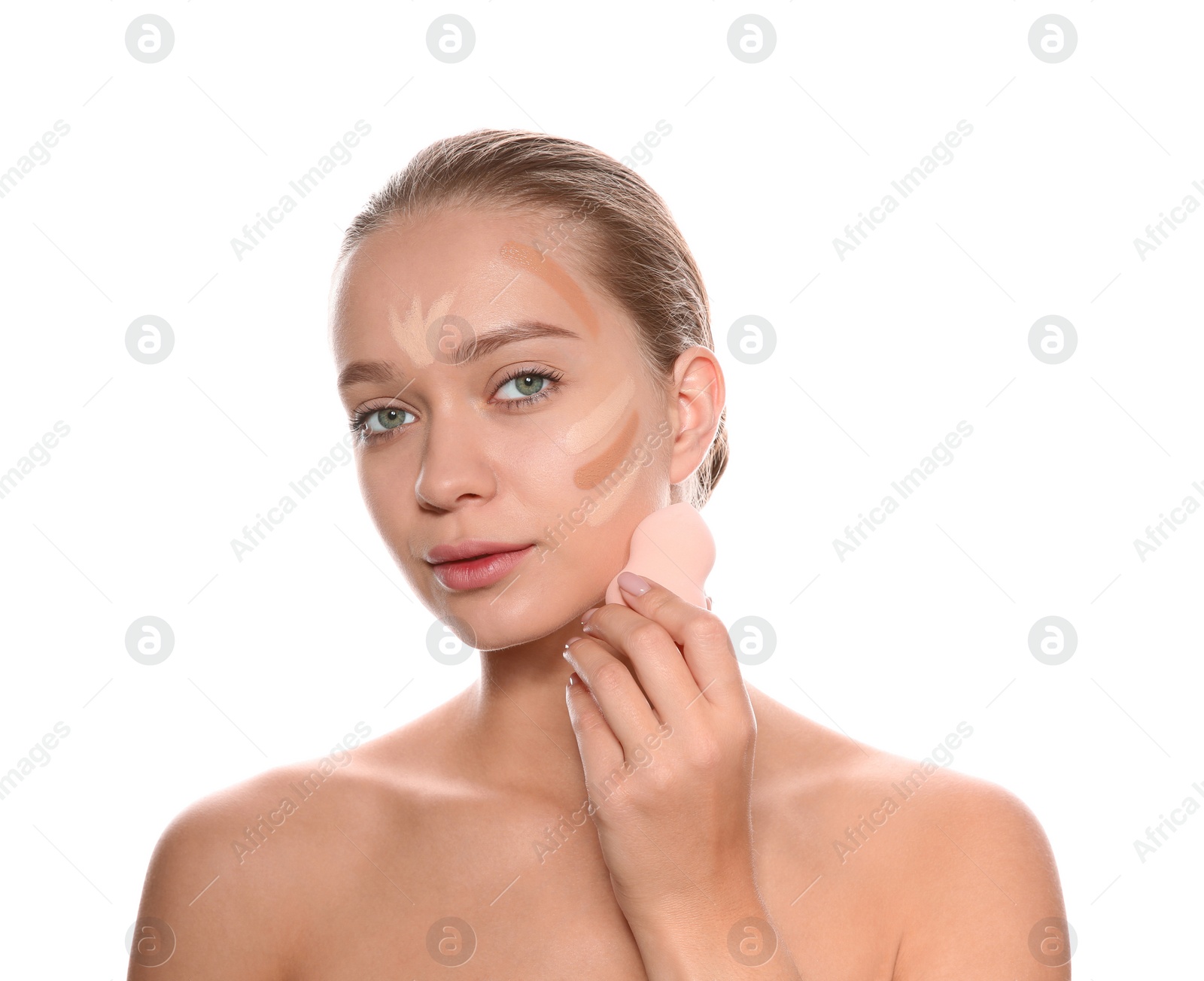 Photo of Young woman applying foundation on her face against white background