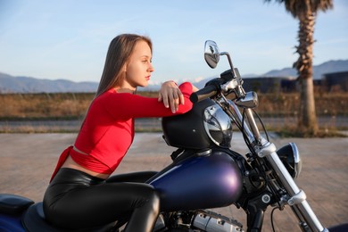 Photo of Beautiful young woman with helmet sitting on motorcycle outdoors