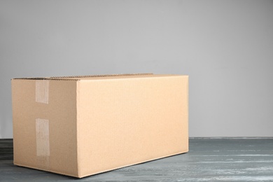 Photo of Cardboard box on grey wooden table against beige background, space for text