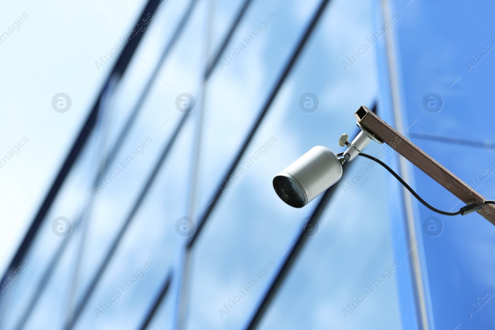 Photo of Modern CCTV security camera on building wall outdoors. Space for text