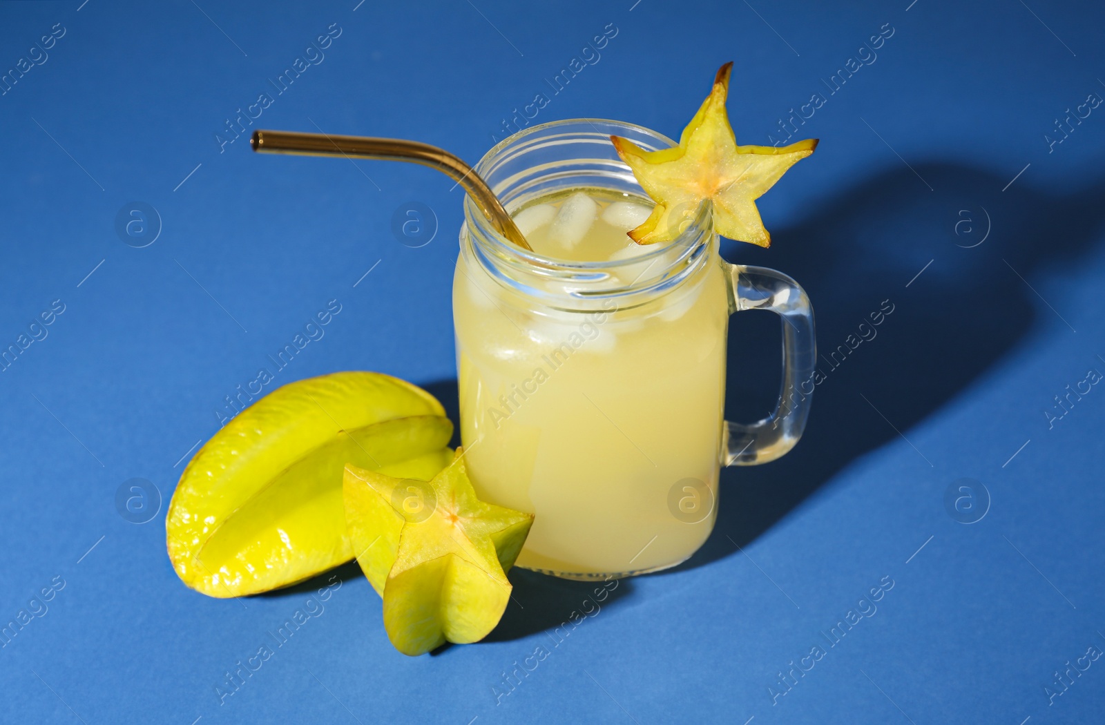 Photo of Delicious carambola juice and fresh fruits on blue background