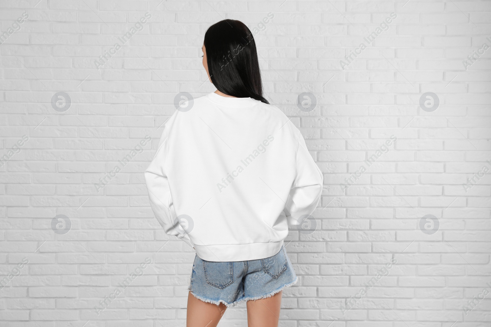 Photo of Young woman in sweater at brick wall. Mock up for design