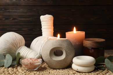 Photo of Aromatherapy. Scented candles and spa products on wicker mat, closeup