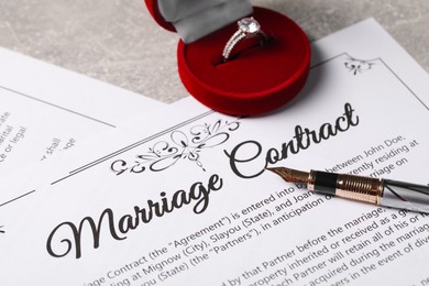 Photo of Marriage contract, fountain pen and ring with gemstone on grey table