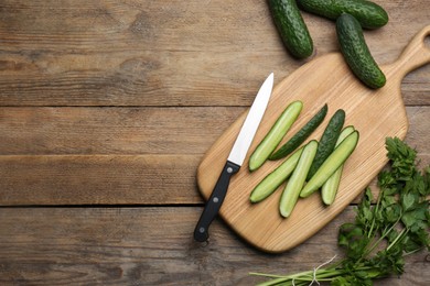 Photo of Fresh ripe cucumbers and parsley on wooden table, flat lay. Space for text