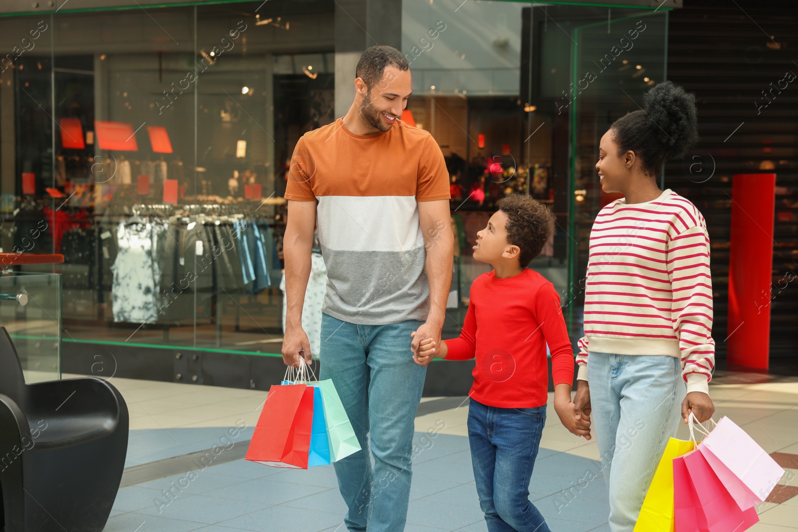 Photo of Family shopping. Happy parents and son with colorful bags in mall