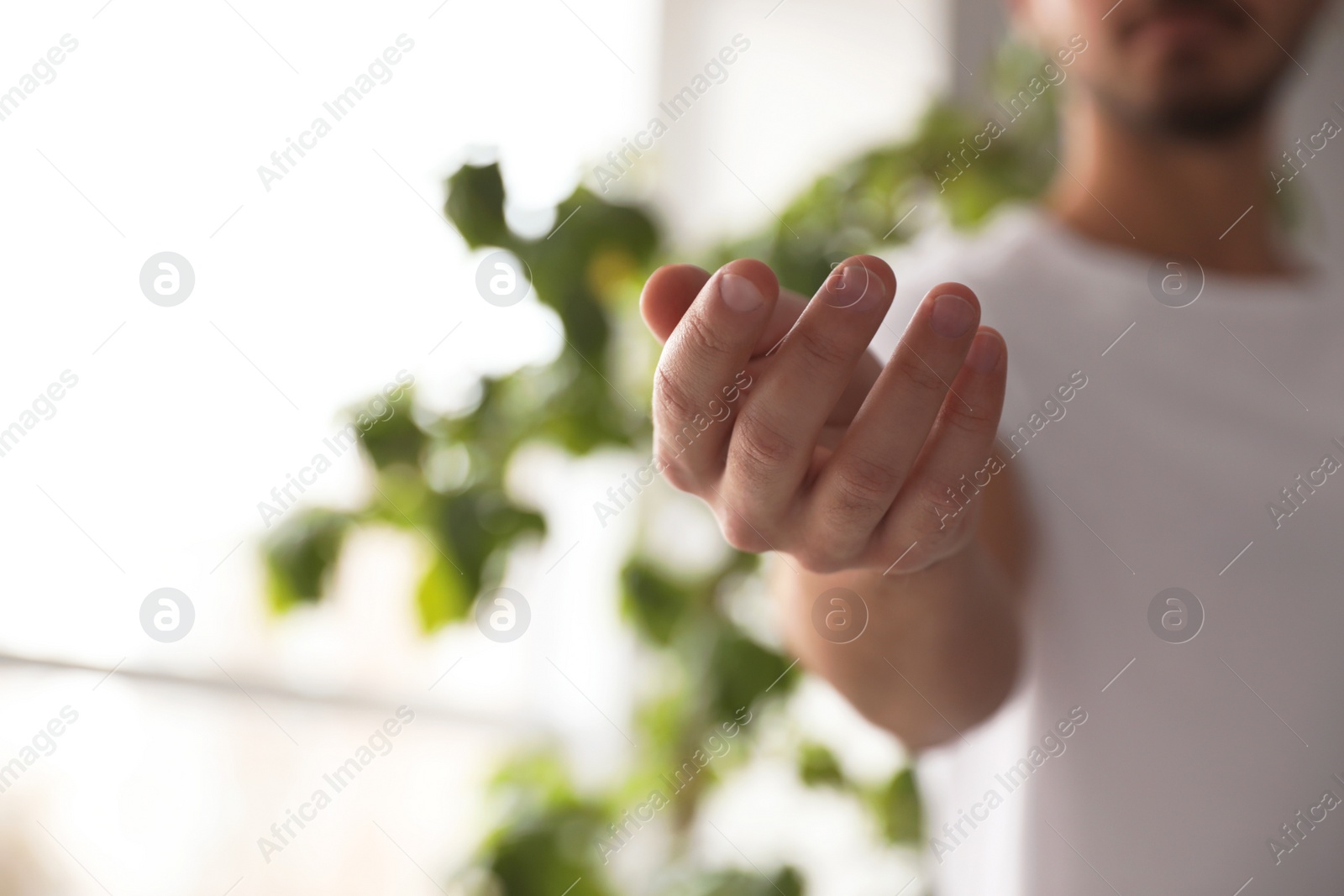 Photo of Man offering helping hand on blurred background, closeup. Space for text