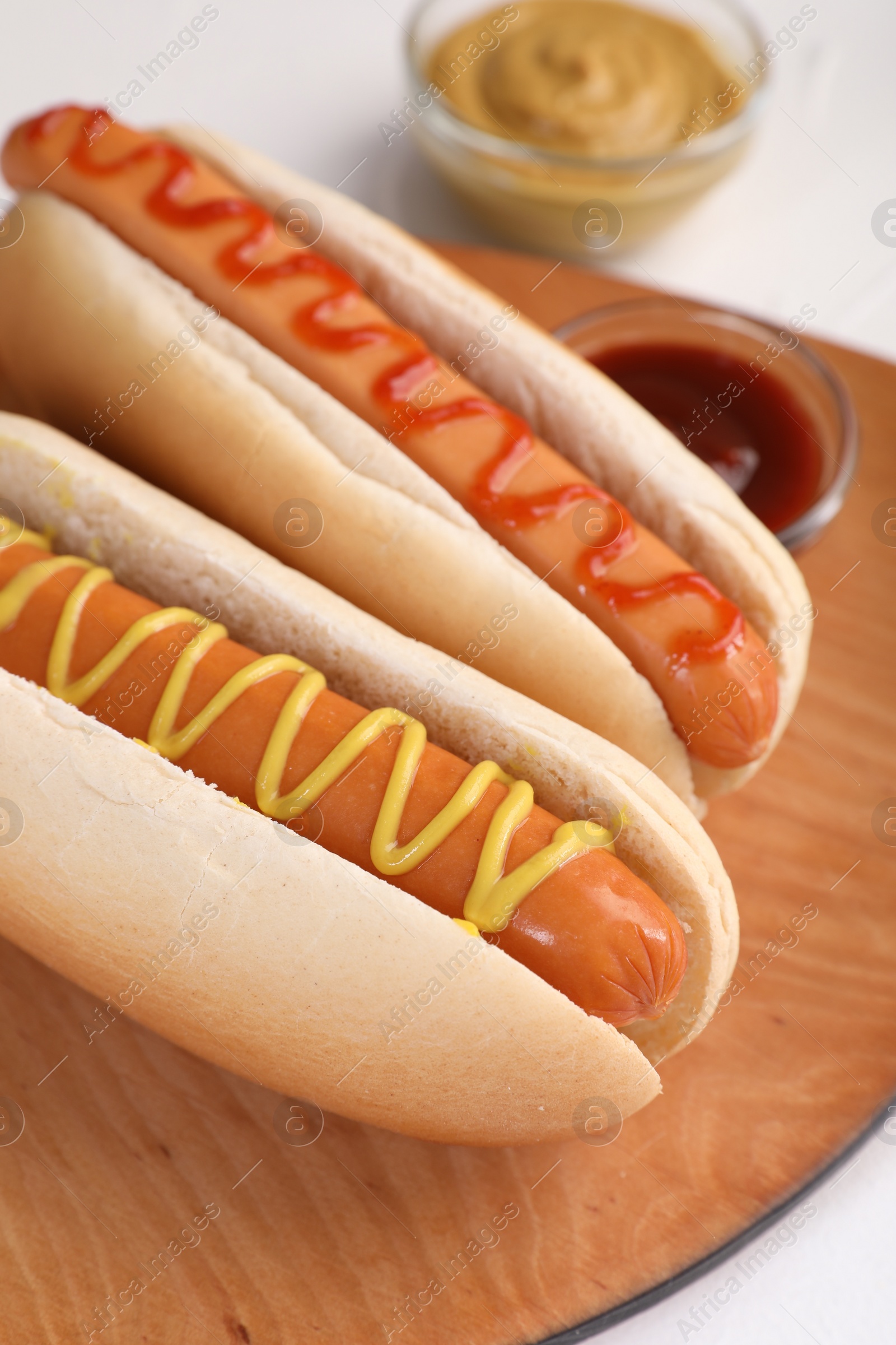 Photo of Tasty hot dogs with ketchup and mustard on white table, closeup