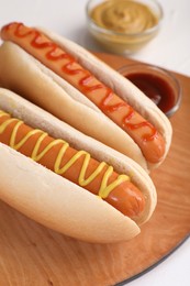 Photo of Tasty hot dogs with ketchup and mustard on white table, closeup