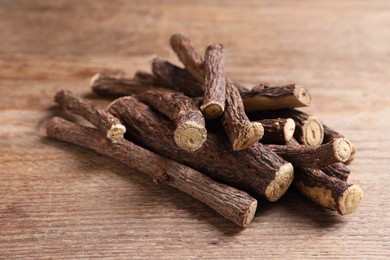 Photo of Dried sticks of liquorice root on wooden table, closeup