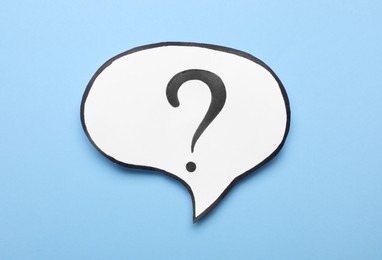 Photo of Paper speech bubble with question mark on light blue background, top view