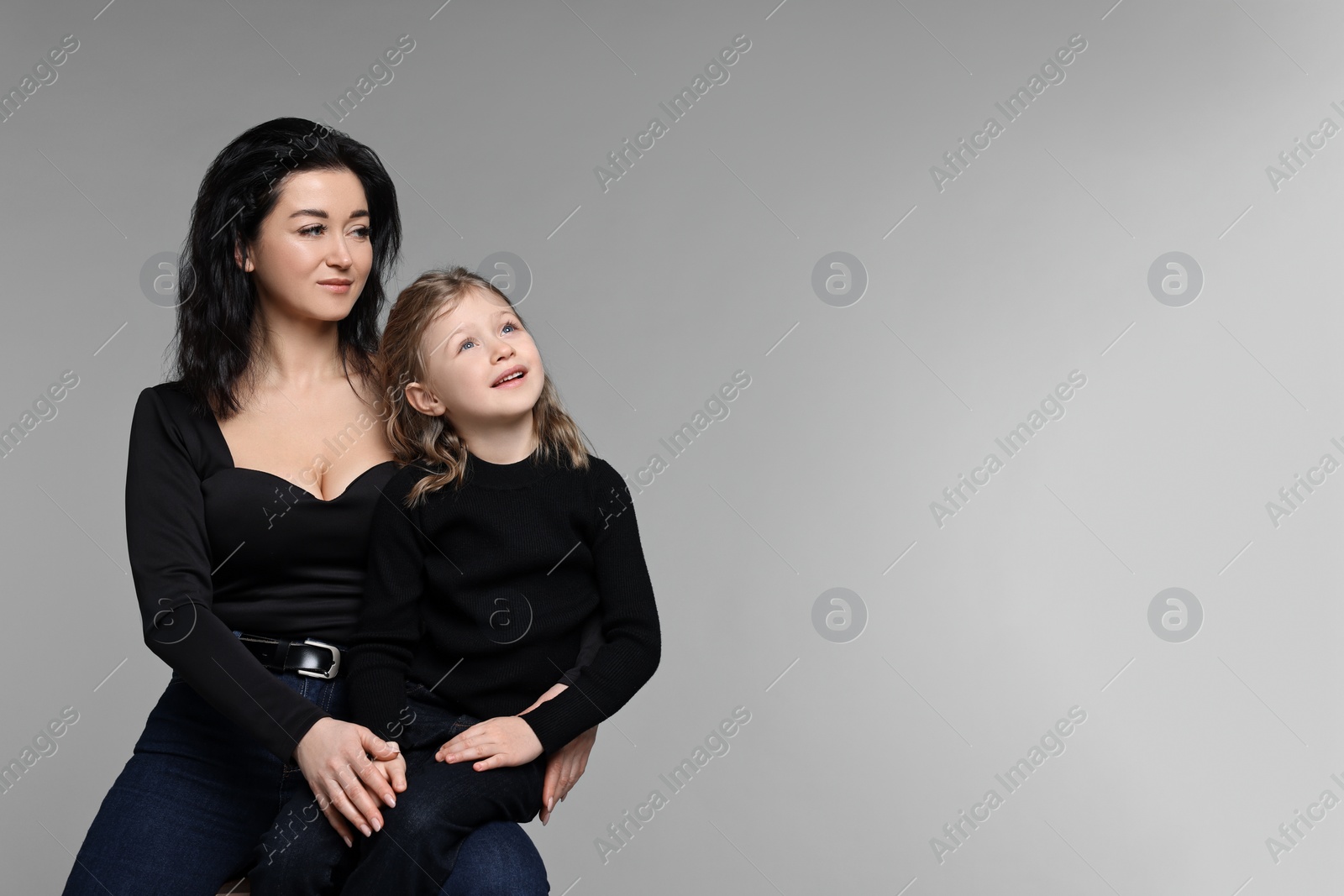 Photo of Beautiful mother with little daughter on grey background. Space for text