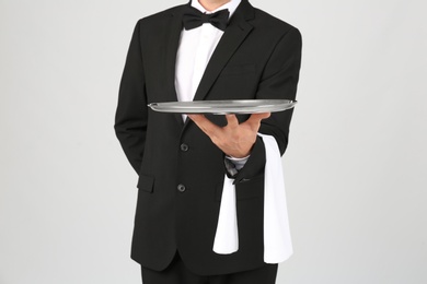 Waiter holding metal tray on light background