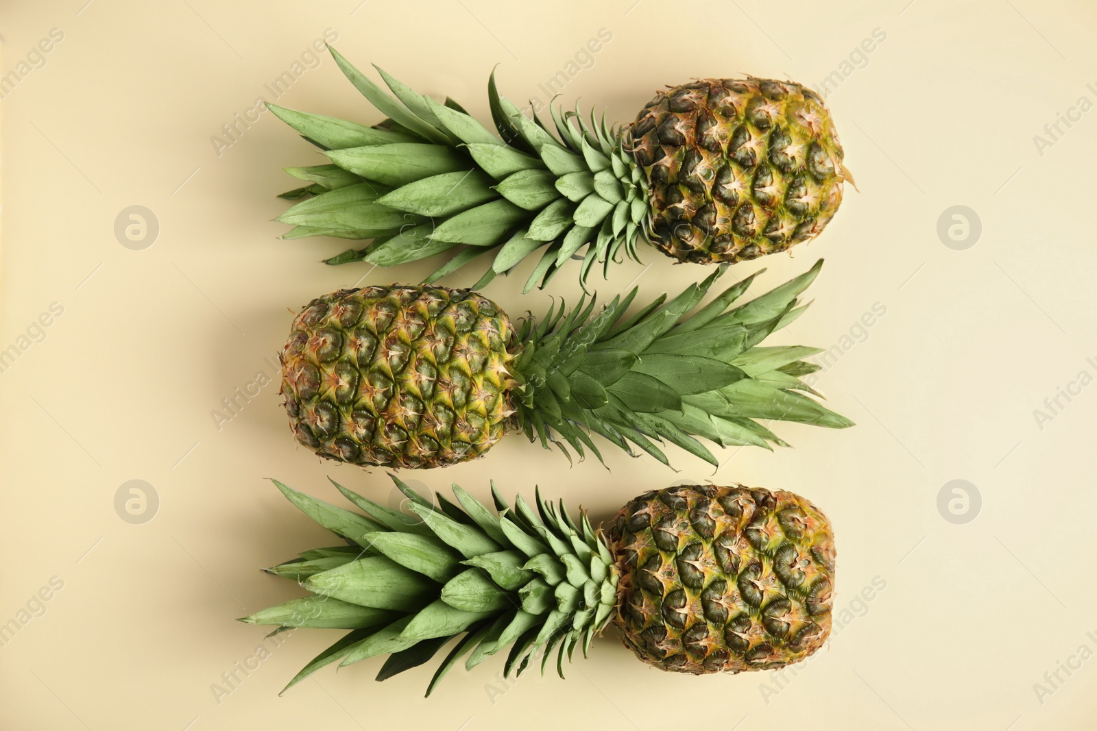 Photo of Fresh ripe juicy pineapples on beige background, flat lay