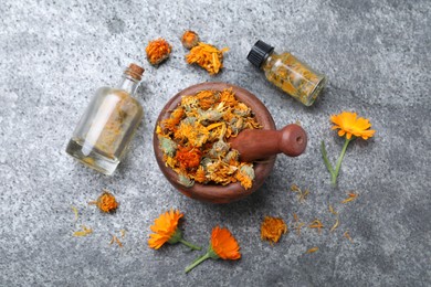 Photo of Dry and fresh calendula flowers with tincture on light grey table, flat lay