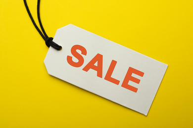 Image of Tag with text SALE on yellow background, top view. Black Friday 