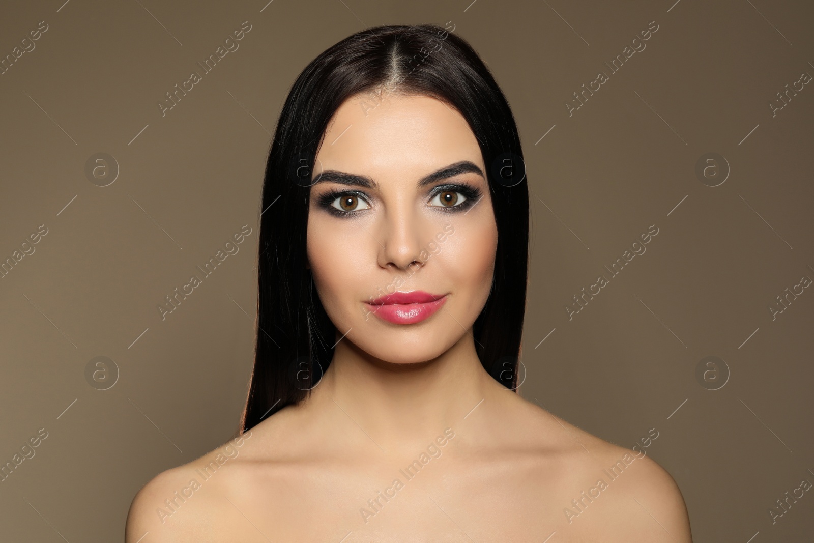 Photo of Beautiful young woman with evening makeup on brown background. Eye shadow product