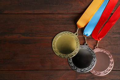 Gold, silver and bronze medals on wooden background, flat lay. Space for design