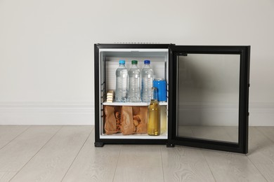 Mini bar filled with food and drinks near white wall indoors