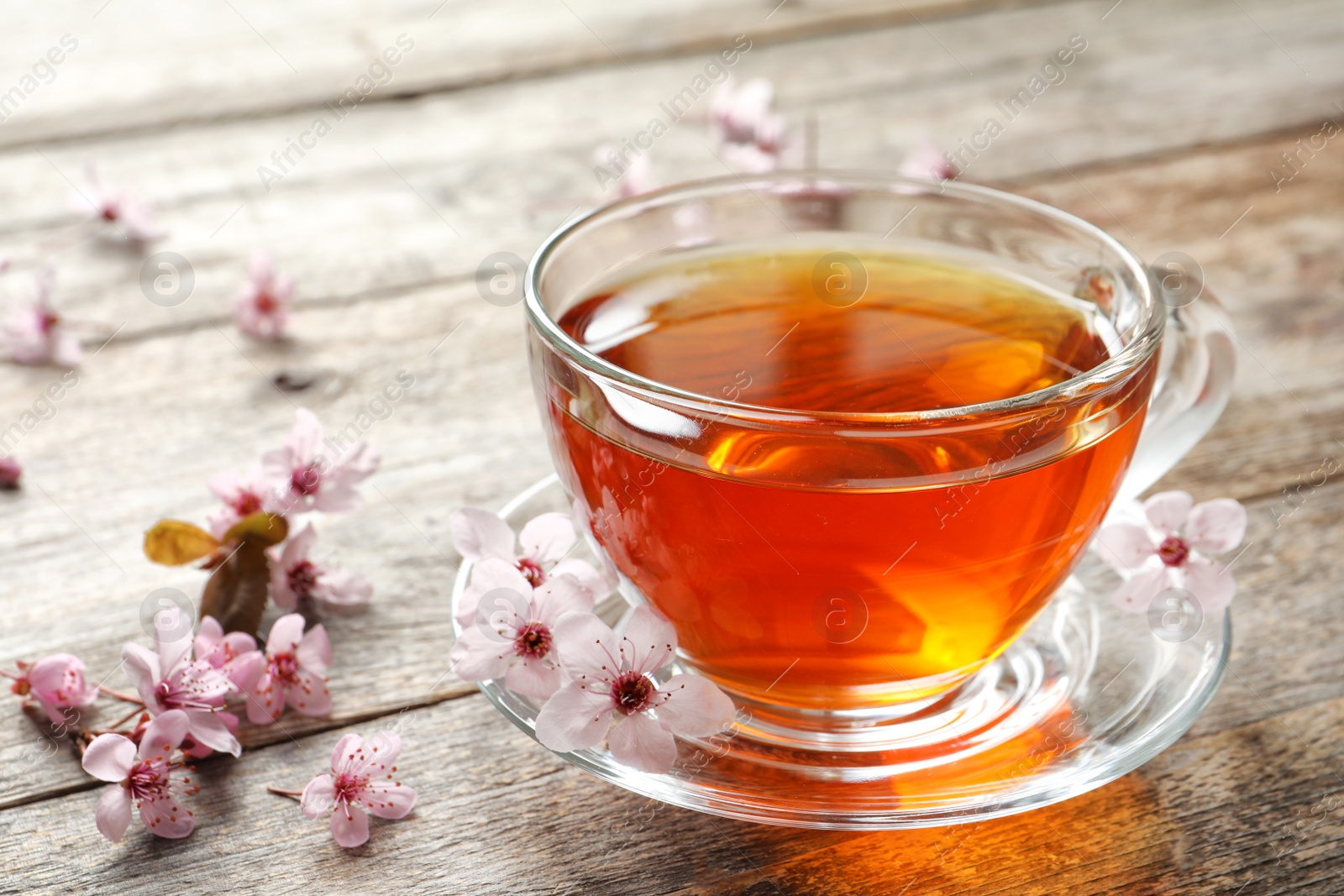 Photo of Cup of tea and blossoming flowers on wooden background