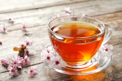 Photo of Cup of tea and blossoming flowers on wooden background