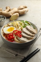 Photo of Delicious ramen in bowl and chopsticks on light textured table, closeup. Noodle soup