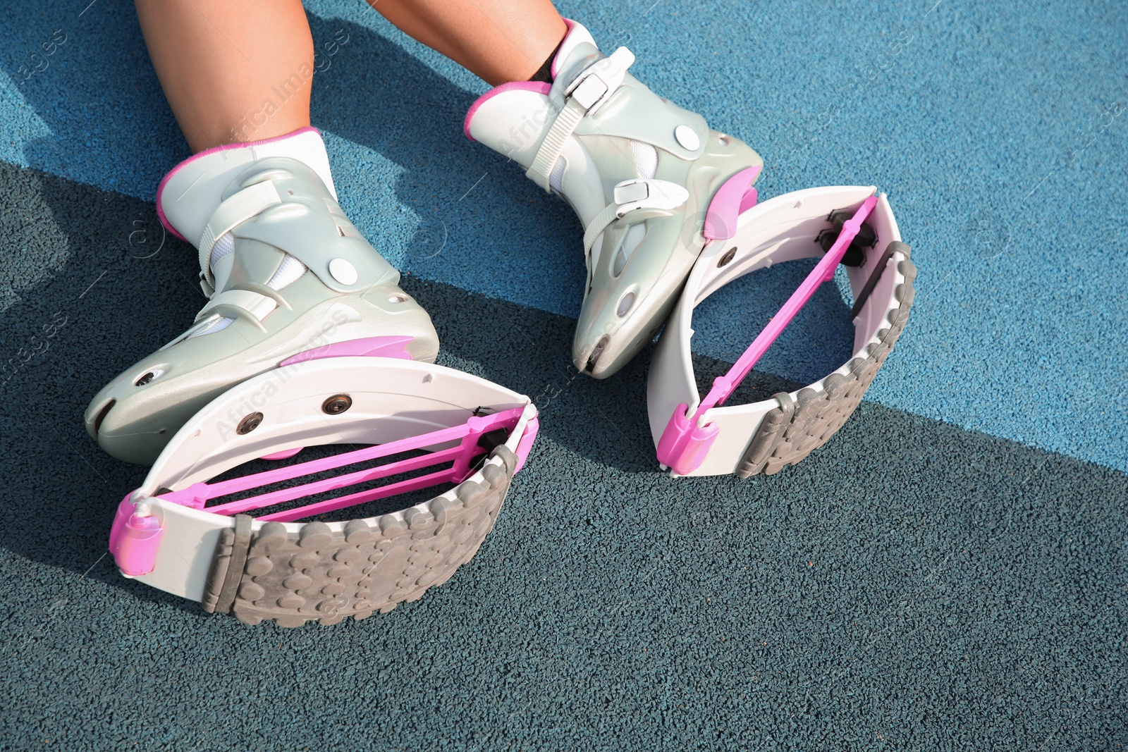 Photo of Woman with kangoo jumping boots on color textured background, closeup