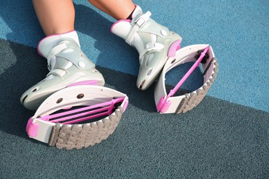 Photo of Woman with kangoo jumping boots on color textured background, closeup