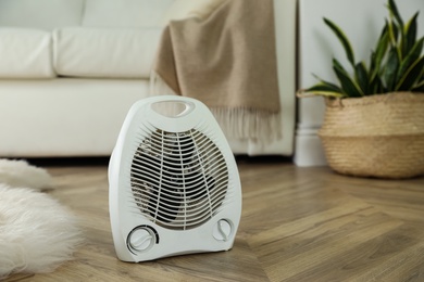 Modern electric fan heater on floor at home. Space for text