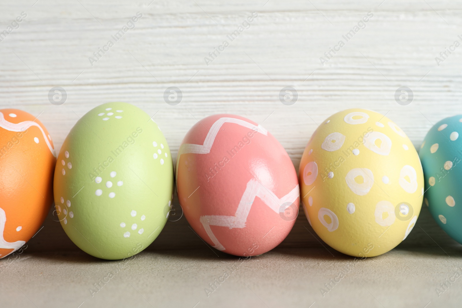 Photo of Colorful painted Easter eggs on table against wooden background, closeup