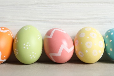 Photo of Colorful painted Easter eggs on table against wooden background, closeup