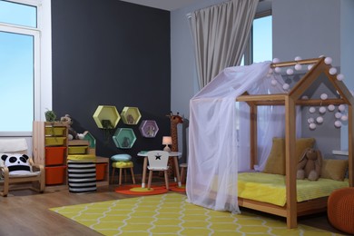 Photo of Stylish child room interior with comfortable house bed and toys