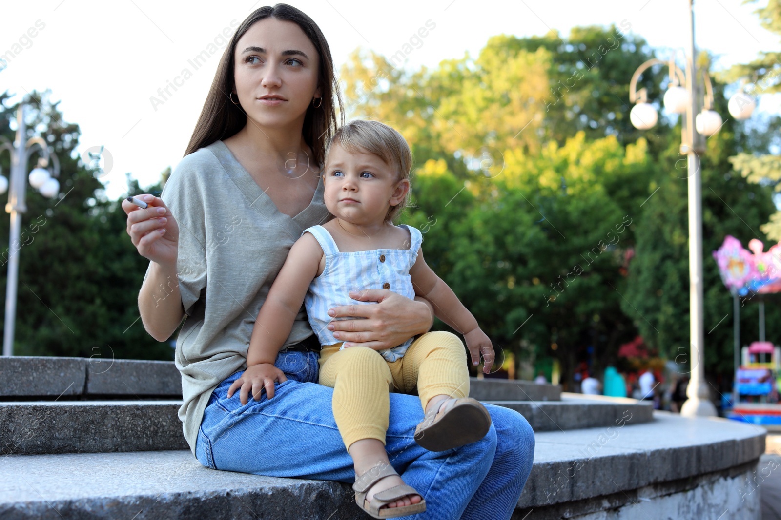 Photo of Mother with cigarette and child outdoors. Don't smoke near kids