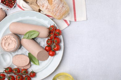 Delicious liver sausages, paste and cherry tomatoes on light grey table, flat lay. Space for text