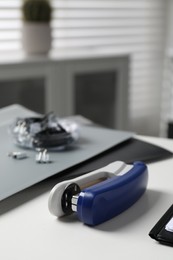 Stapler on white table indoors, closeup view