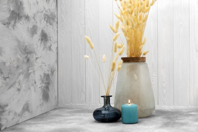 Photo of Vases with beautiful dry flowers, candle and double-sided backdrops in photo studio