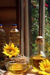 Photo of Organic sunflower oil, seeds and flowers on window sill indoors