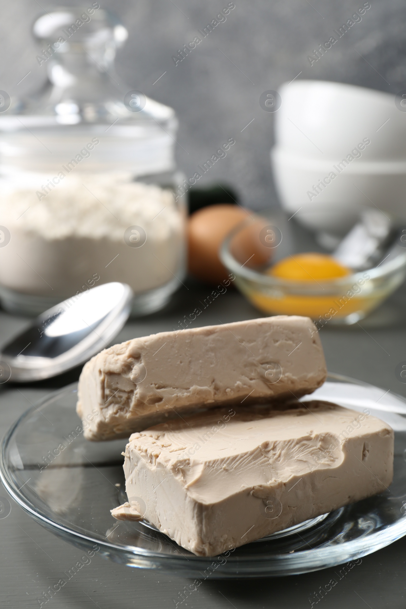 Photo of Compressed yeast, eggs and flour on grey wooden table