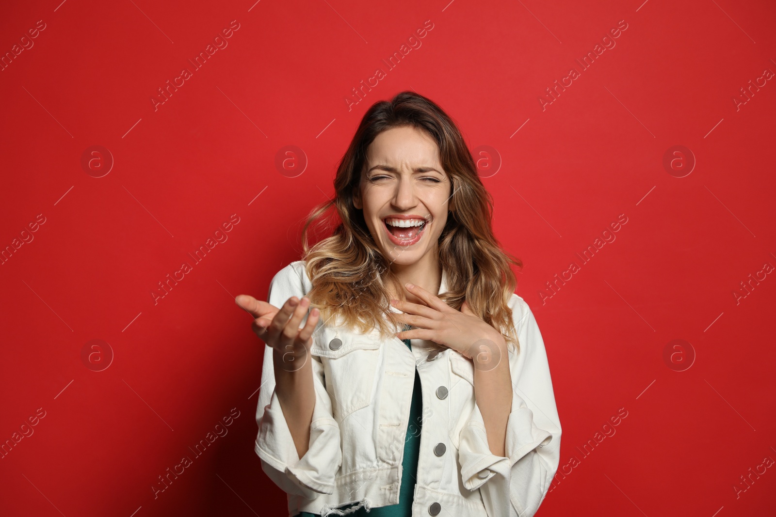 Photo of Cheerful young woman laughing on red background