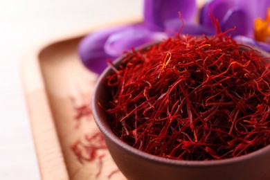 Photo of Dried saffron and crocus flowers on wooden tray, closeup. Space for text