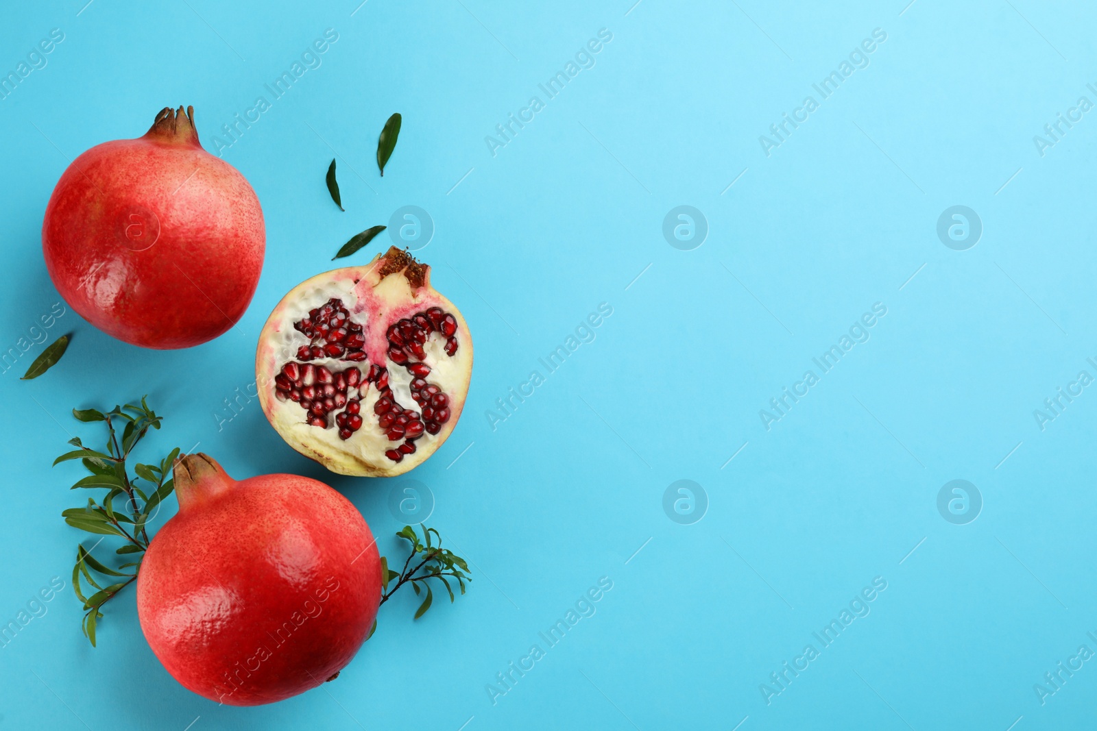 Photo of Flat lay composition with ripe pomegranates on light blue background. Space for text