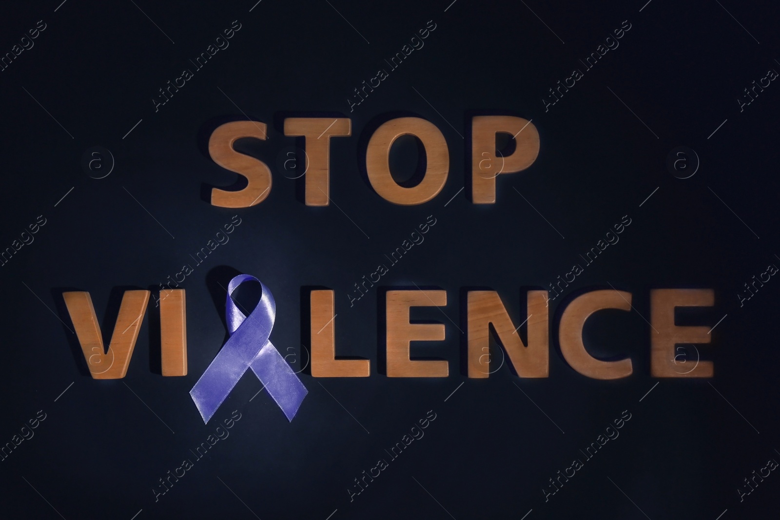 Photo of Purple awareness ribbon and phrase STOP VIOLENCE made of wooden letters on black background, top view