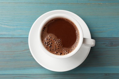 Tasty hot chocolate on light blue wooden table, top view