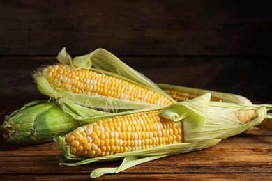 Photo of Tasty sweet corn cobs on wooden table