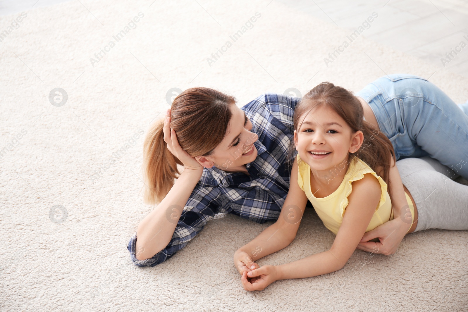 Photo of Cute little girl and her mother lying on cozy carpet at home