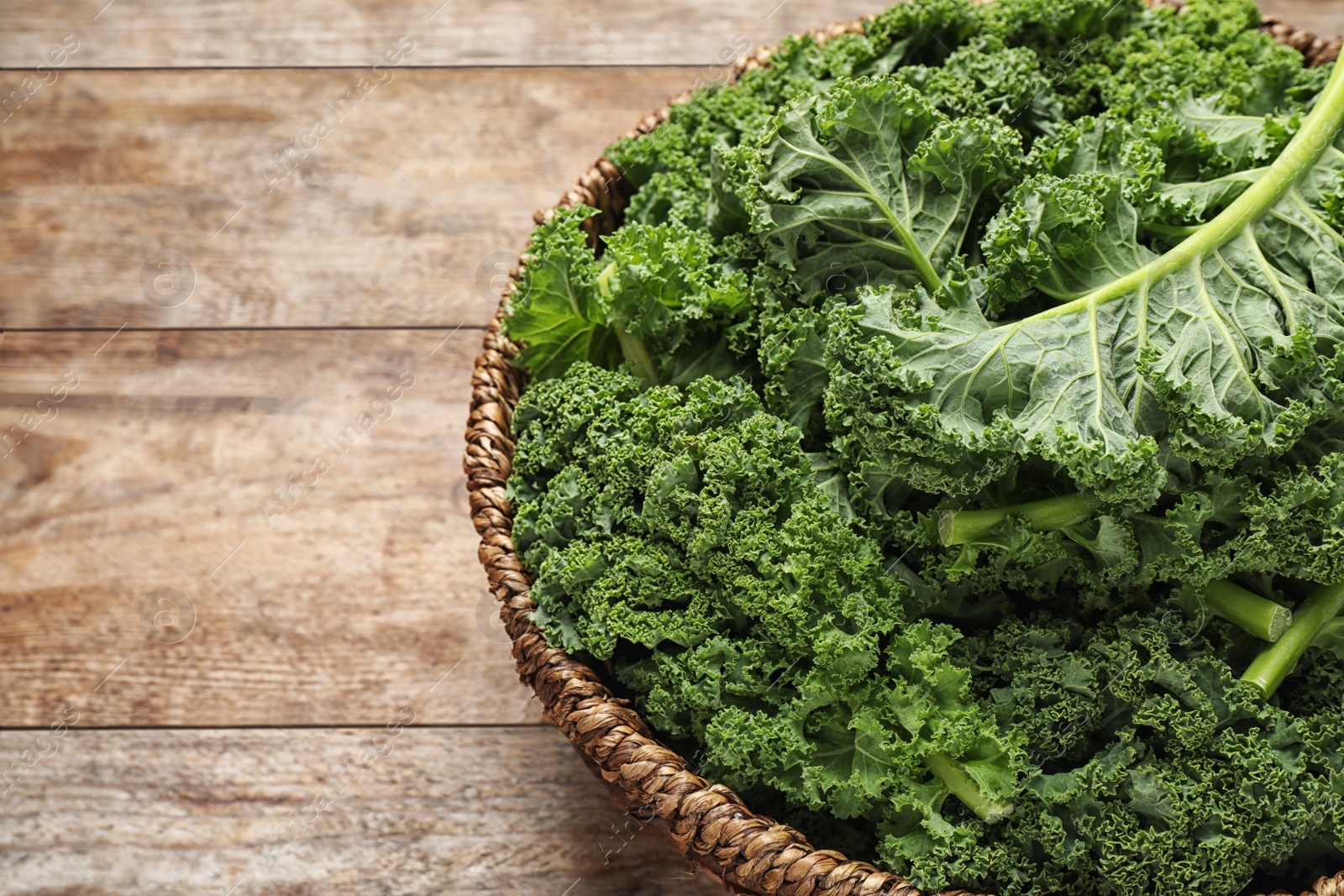 Photo of Fresh kale leaves on wooden table, closeup