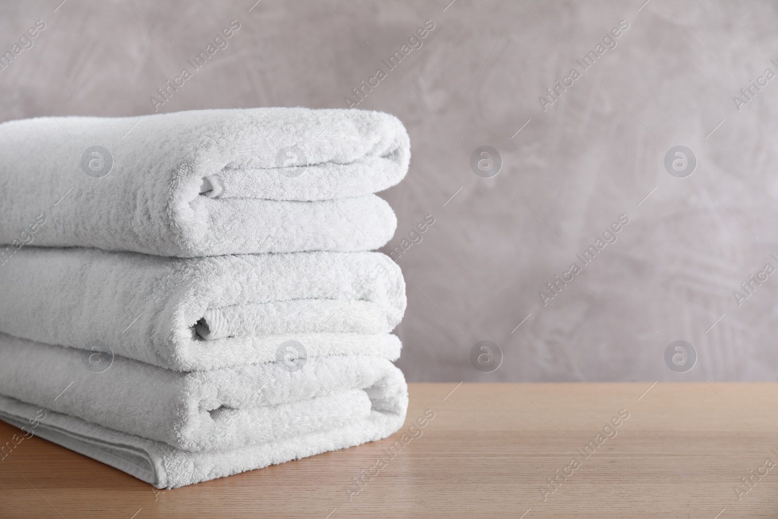 Photo of Stack of clean bath towels on wooden table. Space for text