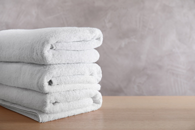 Photo of Stack of clean bath towels on wooden table. Space for text