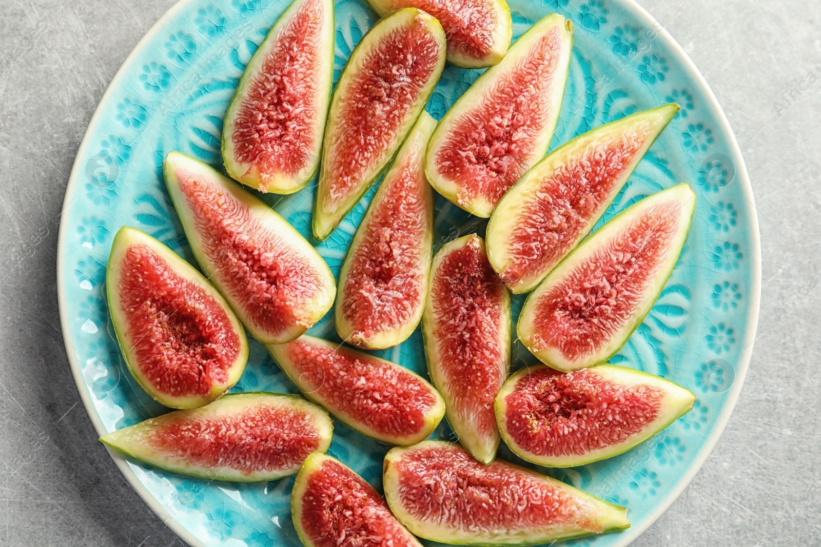 Photo of Plate with fresh ripe fig slices on gray background, top view