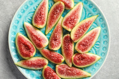 Photo of Plate with fresh ripe fig slices on gray background, top view